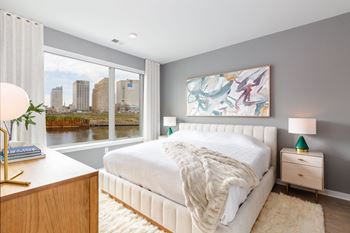 A bedroom with a large window and a white bed